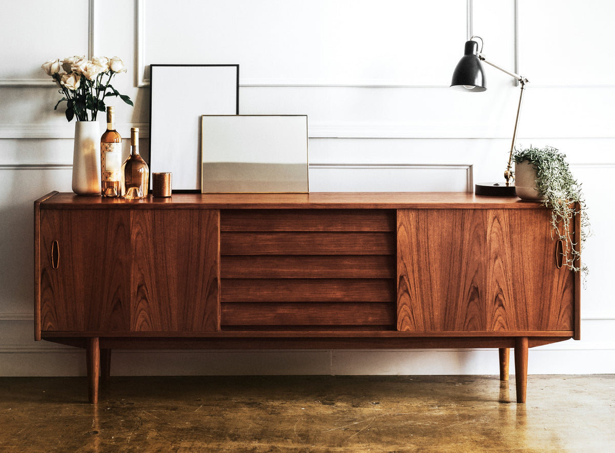 A mid-century modern wooden cabinet styled with accessories