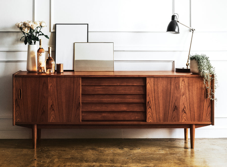 A mid-century modern wooden cabinet styled with accessories