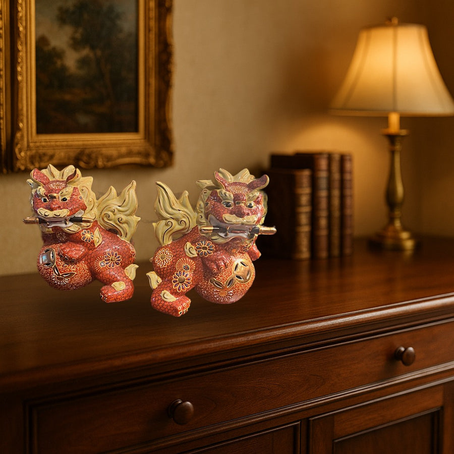 Pair of Japanese Kutani Guardian Lion Figures displayed on a dark wood sideboard